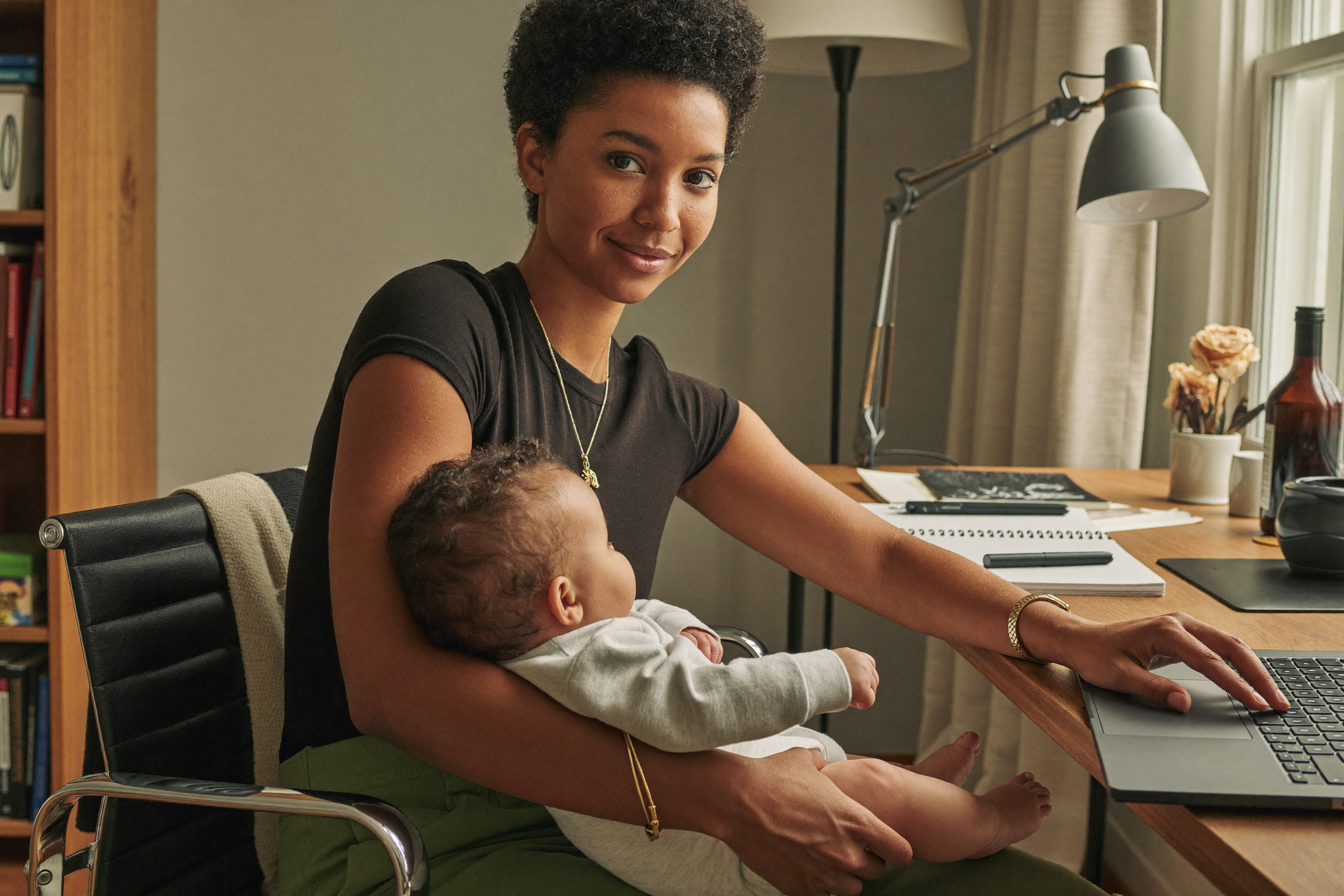 Mother working on laptop while holding her baby